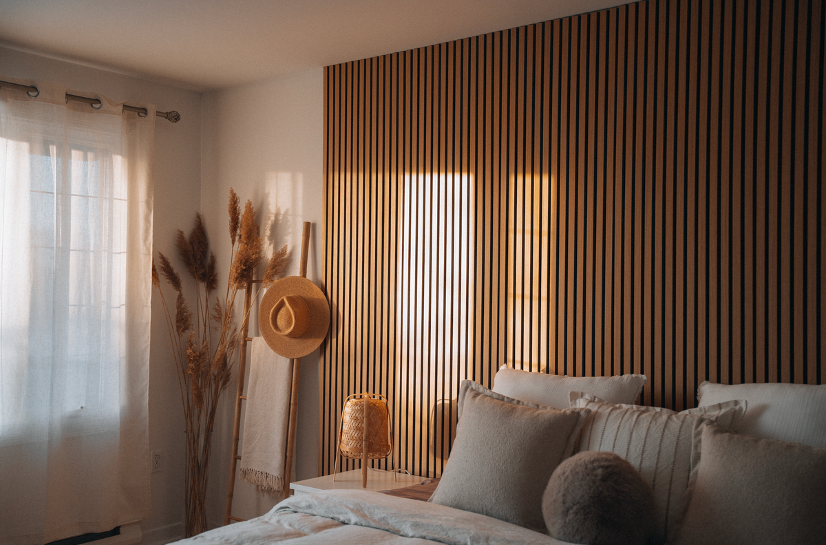 Cozy bedroom with wooden slat wall, bed with pillows, and decorative elements.